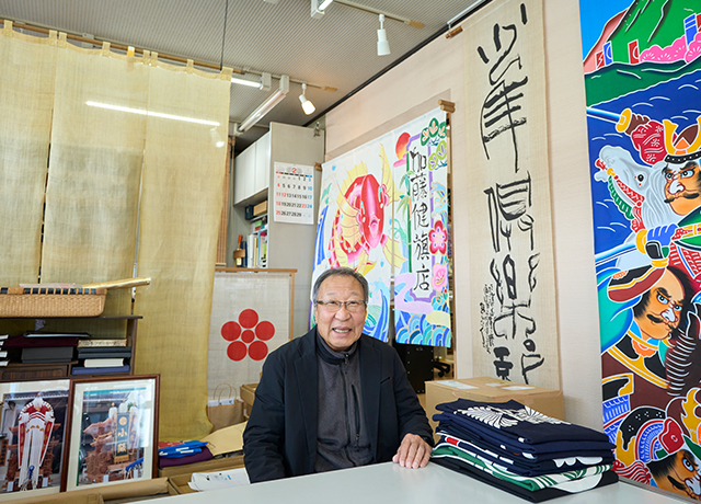 笑顔で出迎えてくれる、2代目当主、加藤隆司さん。お店の商談スペースに飾られている旗や暖簾も手描きの京友禅など1点ものばかり。