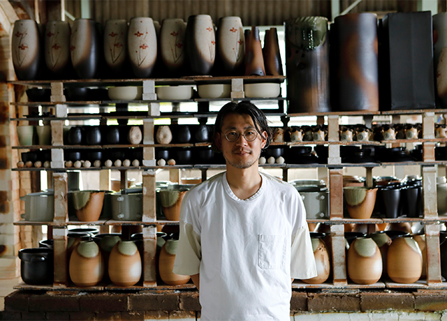 信楽焼の土味を活かした商品を前に立つ、明山窯代表の石野伸也さん